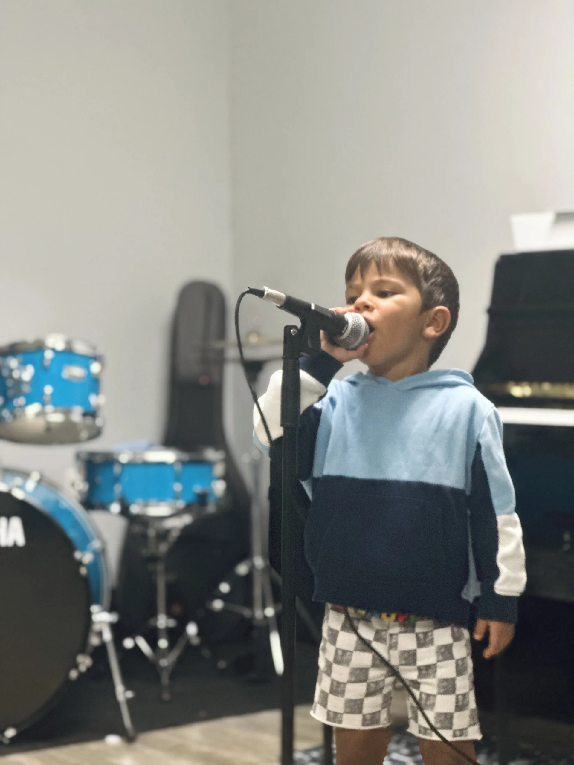 Young male student singing at microphone in music studio.