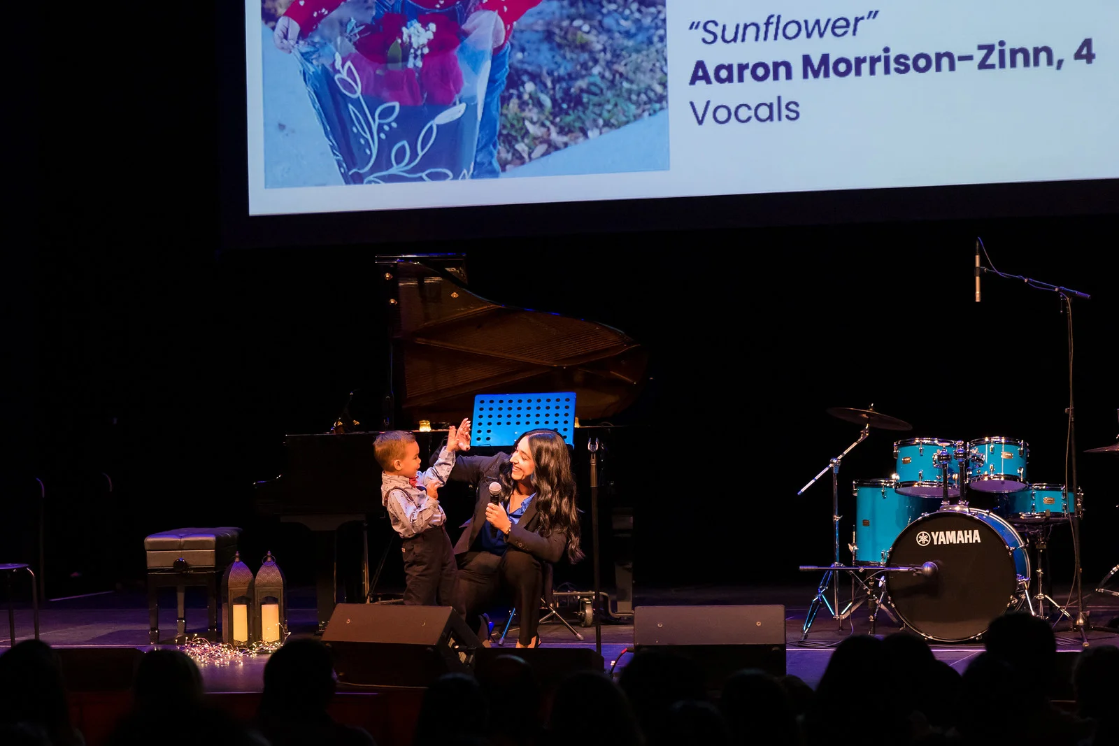 young student on stage with adult high fiving.