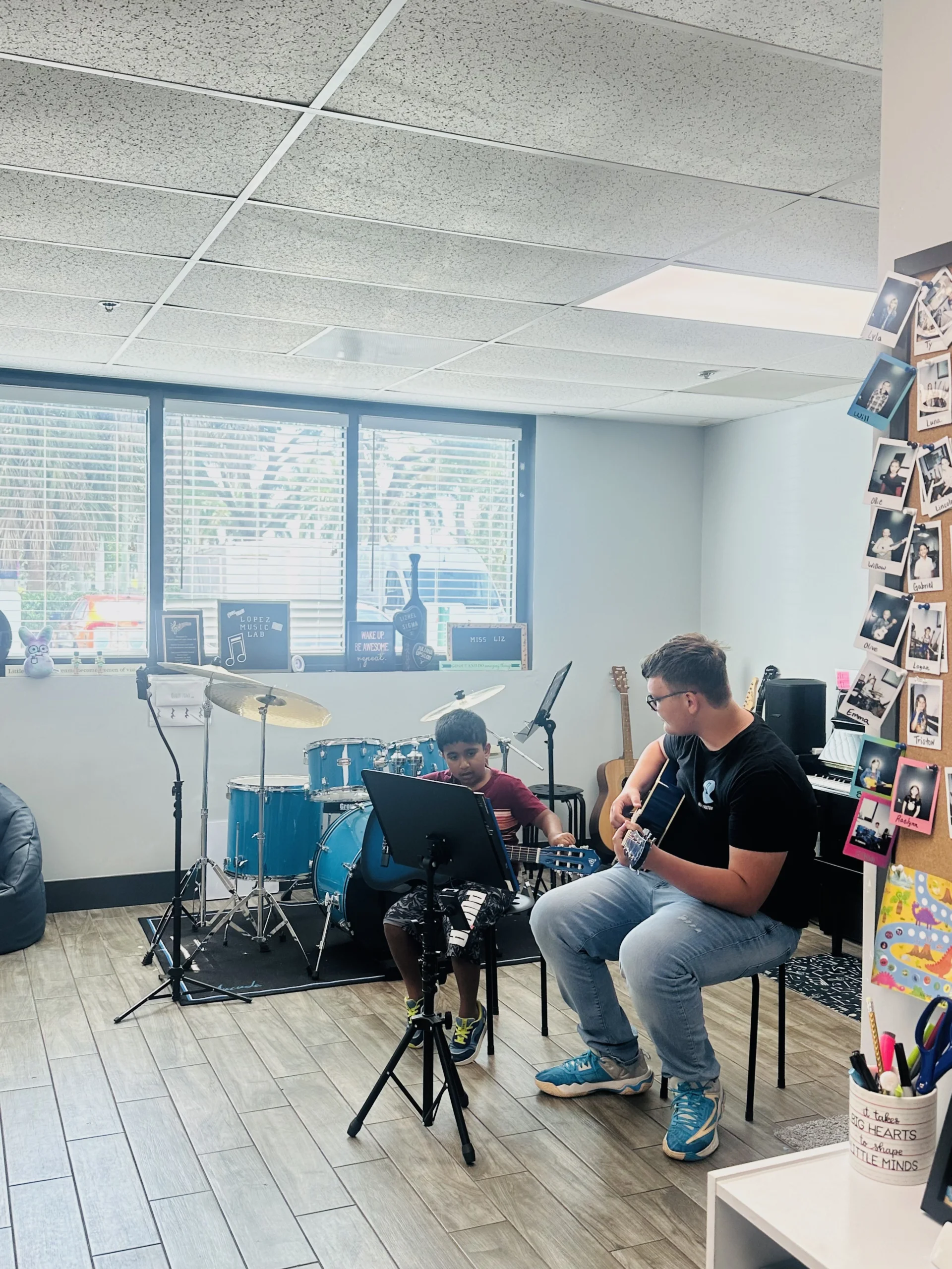 Young student and adult playing guitars in music studio.