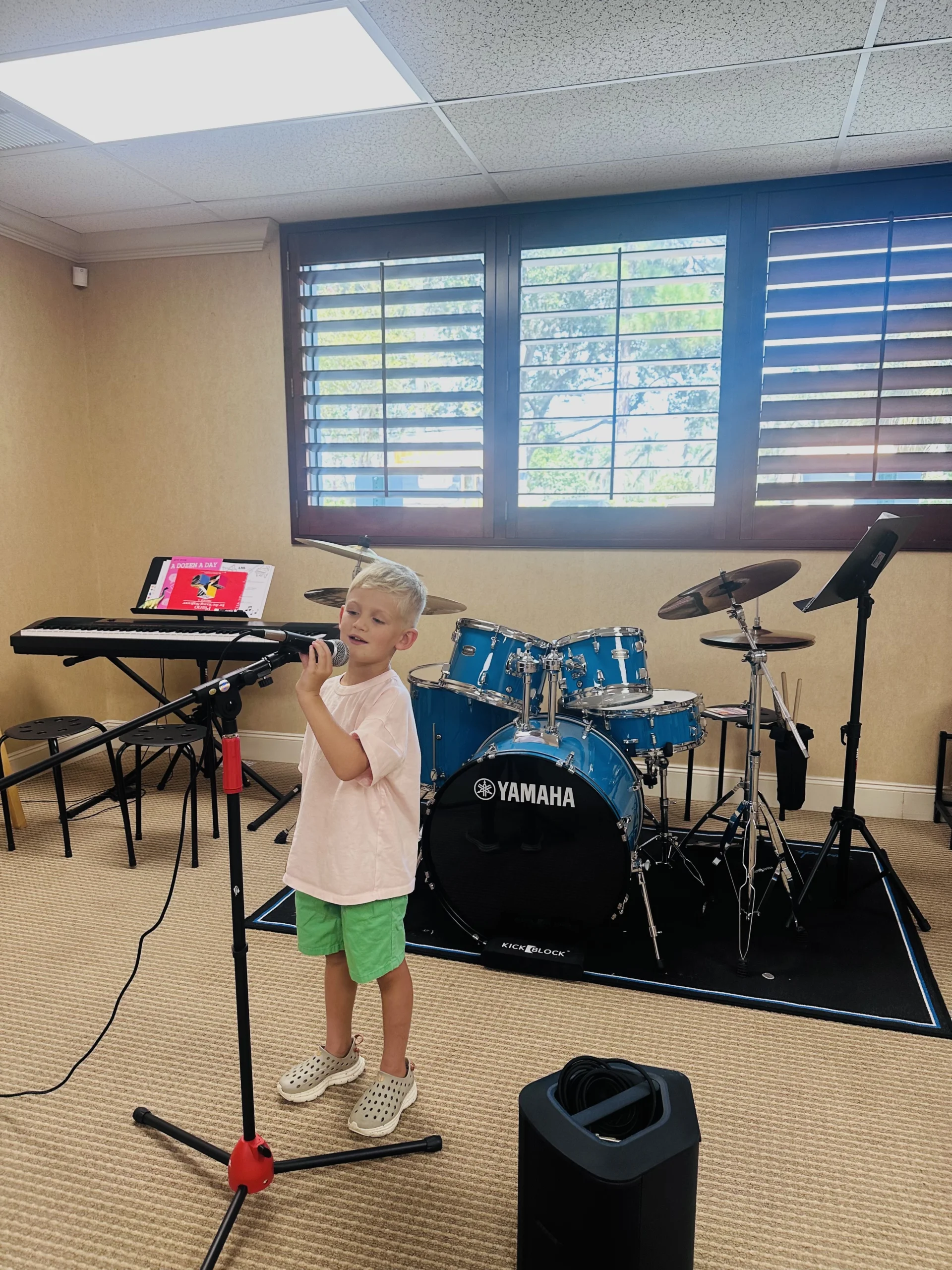 Young student singing at microphone in music studio.