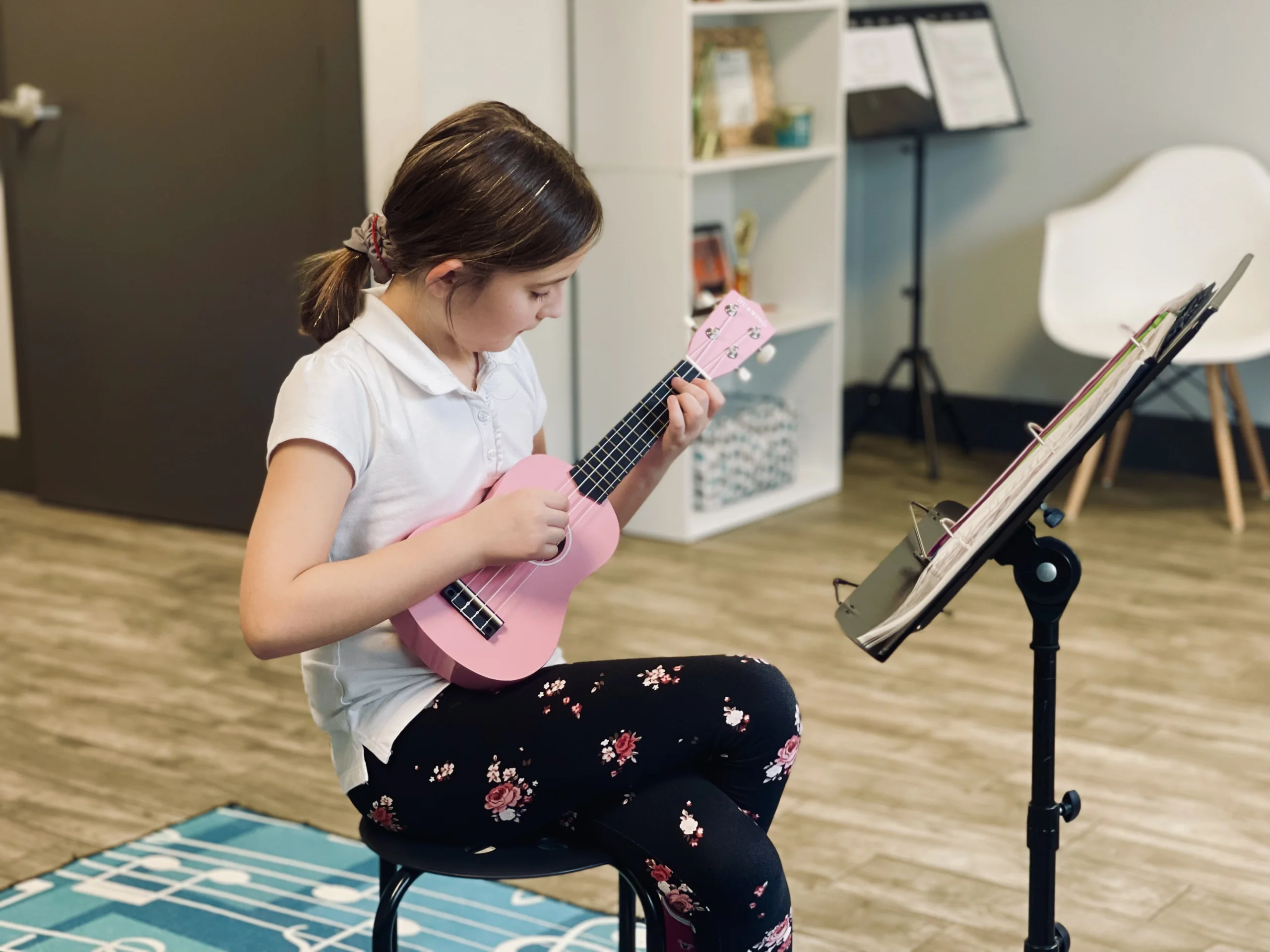 Young female student playing ukulele in music studio.