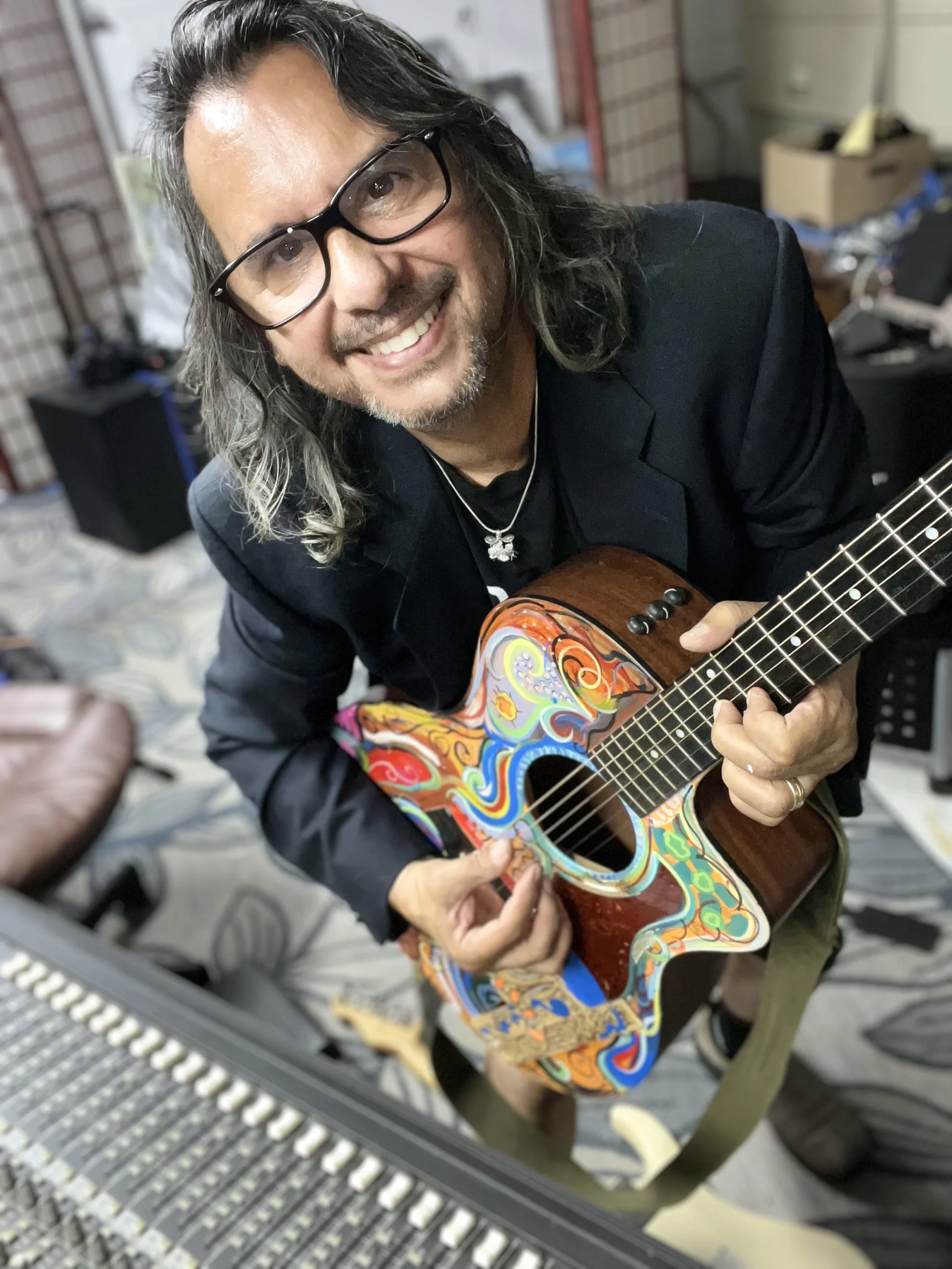 Bobby G smiling holding colorful guitar.