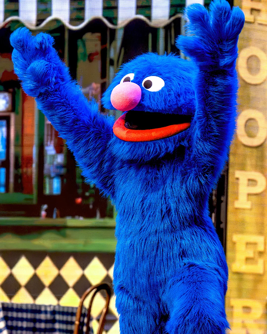 Grover Monster holds up arms over head.