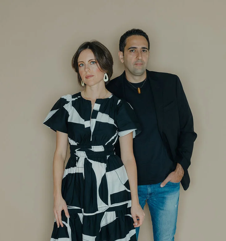 Indigo Dreamers group pose for camera. Women wearing white and black dress while man wears dark top and blue jeans.