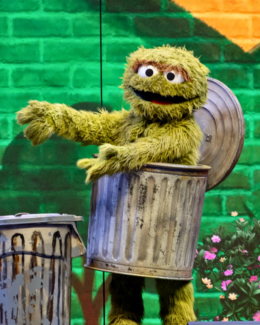 Oscar the Grouch wearing a trash can on stage.