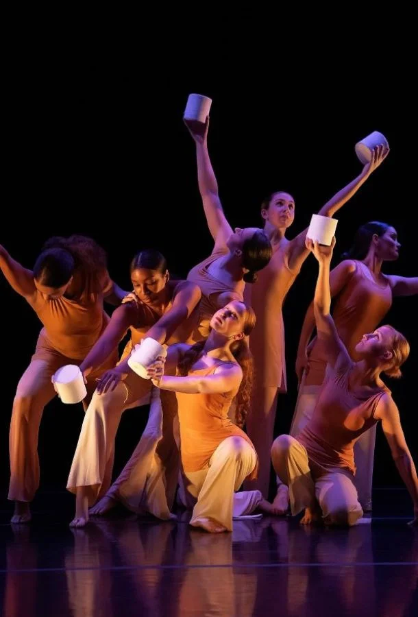 dance students in pose while holding white cans.