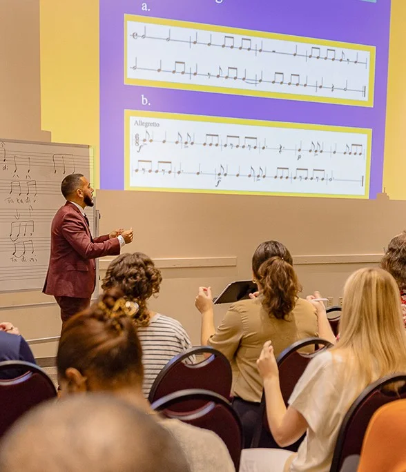 Instructor presents musical notation to educators during a music education workshop.