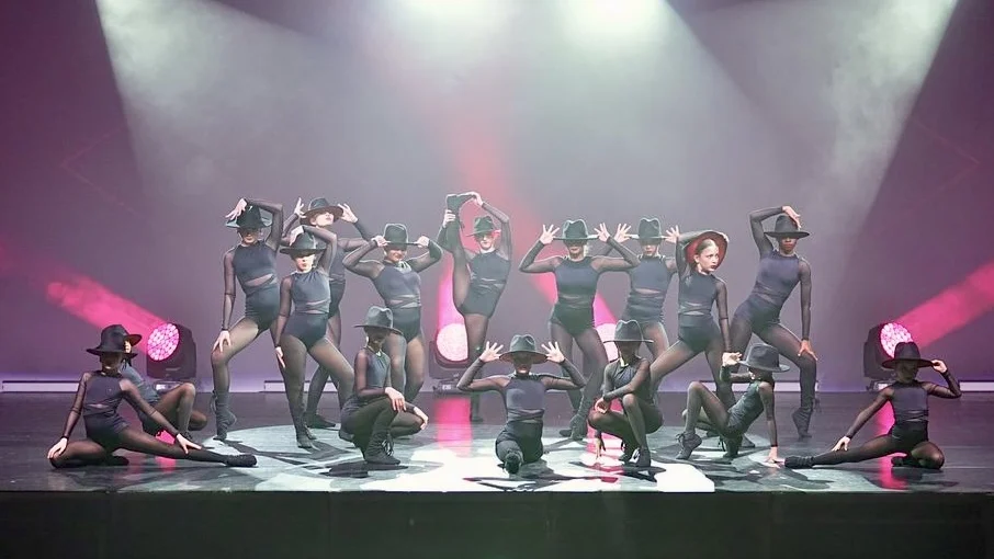 Group of dancers on stage in different poses.