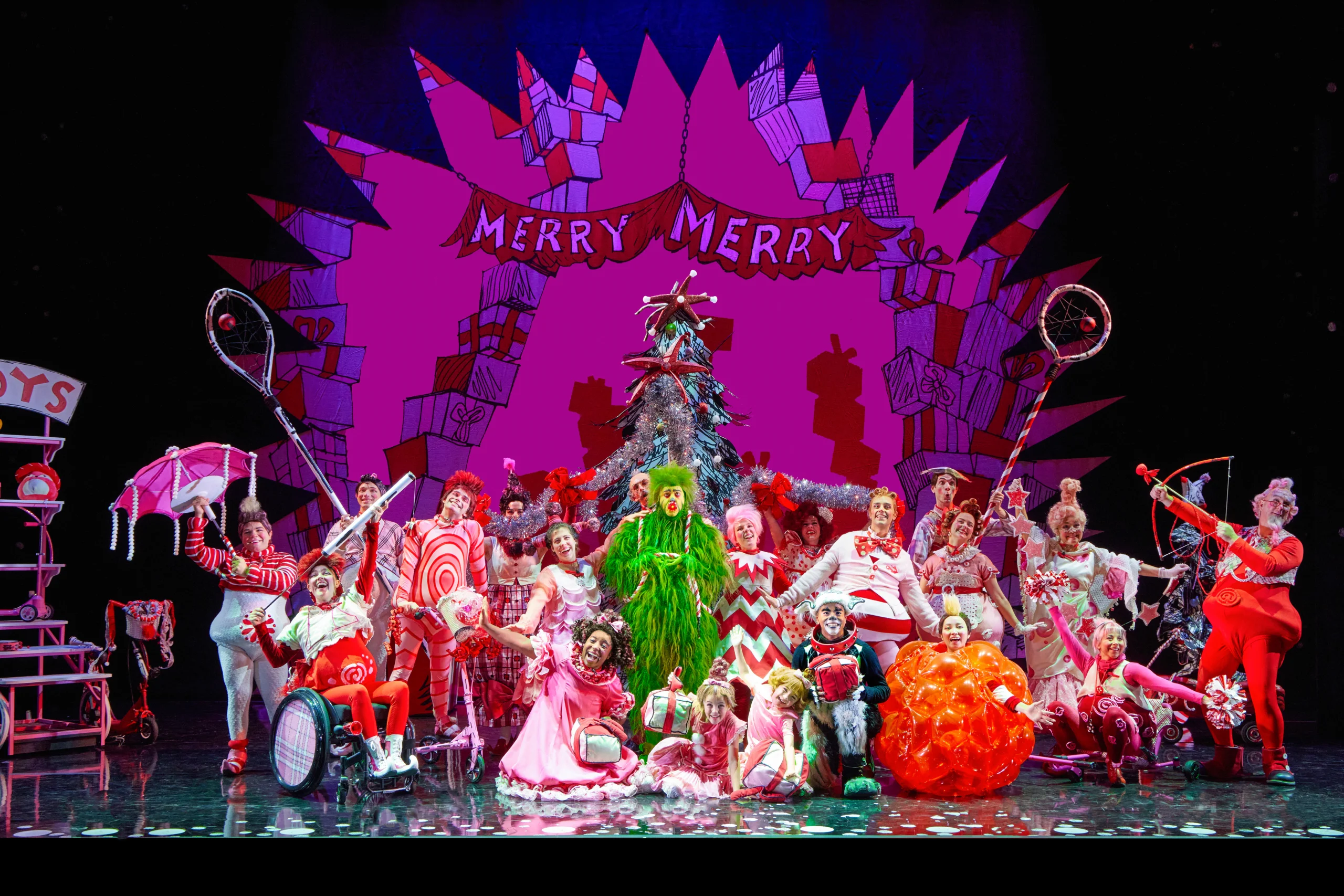 The GRINCH and Cast pose in front of 'Merry Merry backdrop.