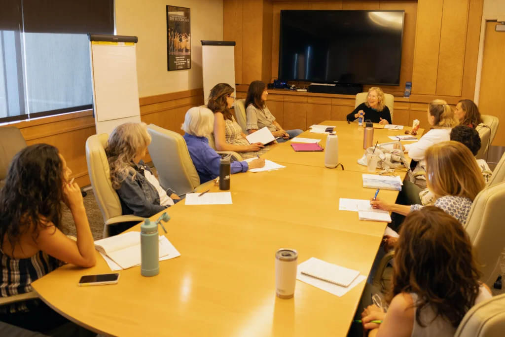 Woman teaching writing course to a group of adults in a conference room.