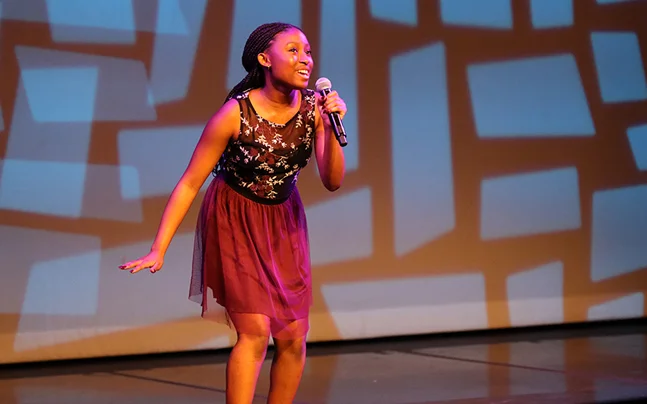 Kid on stage singing solo on stage.