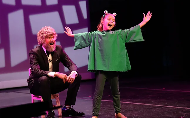 Two kids on stage singing on stage.