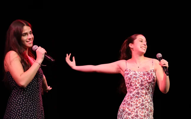 Two kids on stage singing on stage.
