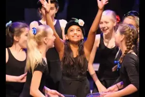 Kids performing on stage smiling.