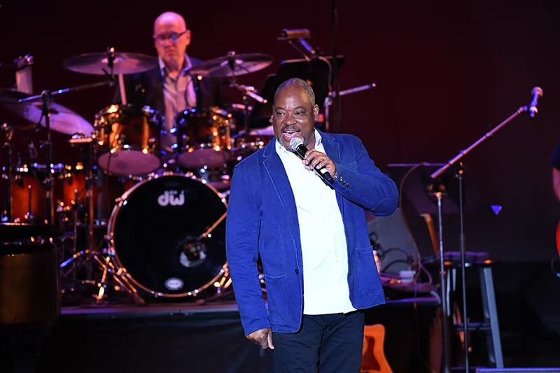 Lead singer performing on stage in front of drum kit during energetic rock concert show.