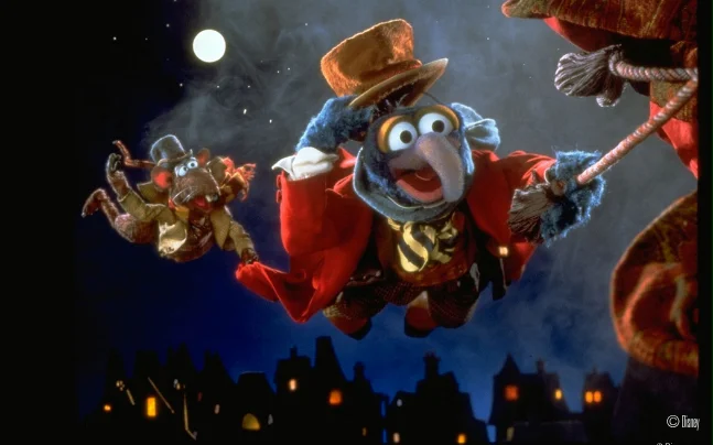 Disney’s The Muppet Christmas Carol Live in Concert featuring a live orchestra performing the film score beneath a large screen showing scenes from the holiday classic, including Gonzo and other Muppet characters.