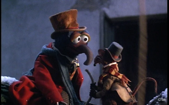 Disney’s The Muppet Christmas Carol Live in Concert featuring a live orchestra performing the film score beneath a large screen showing scenes from the holiday classic, including Gonzo and other Muppet characters.