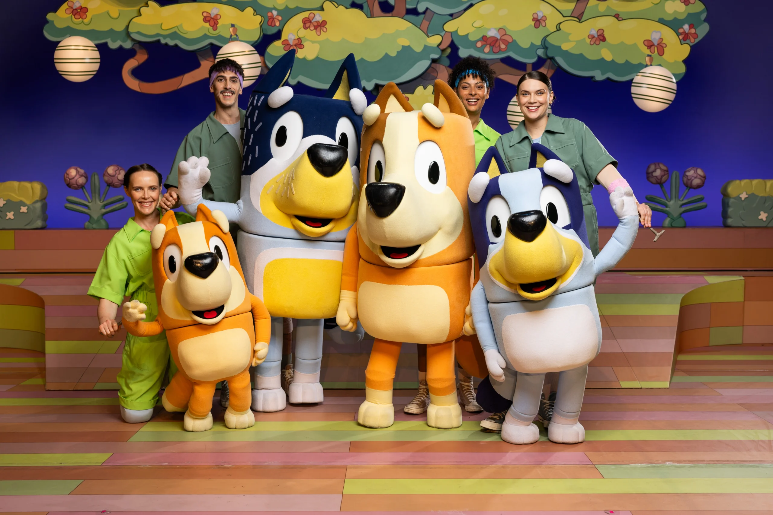 Bluey, Bingo, Bandit, and Chilli character puppets with cast members onstage.