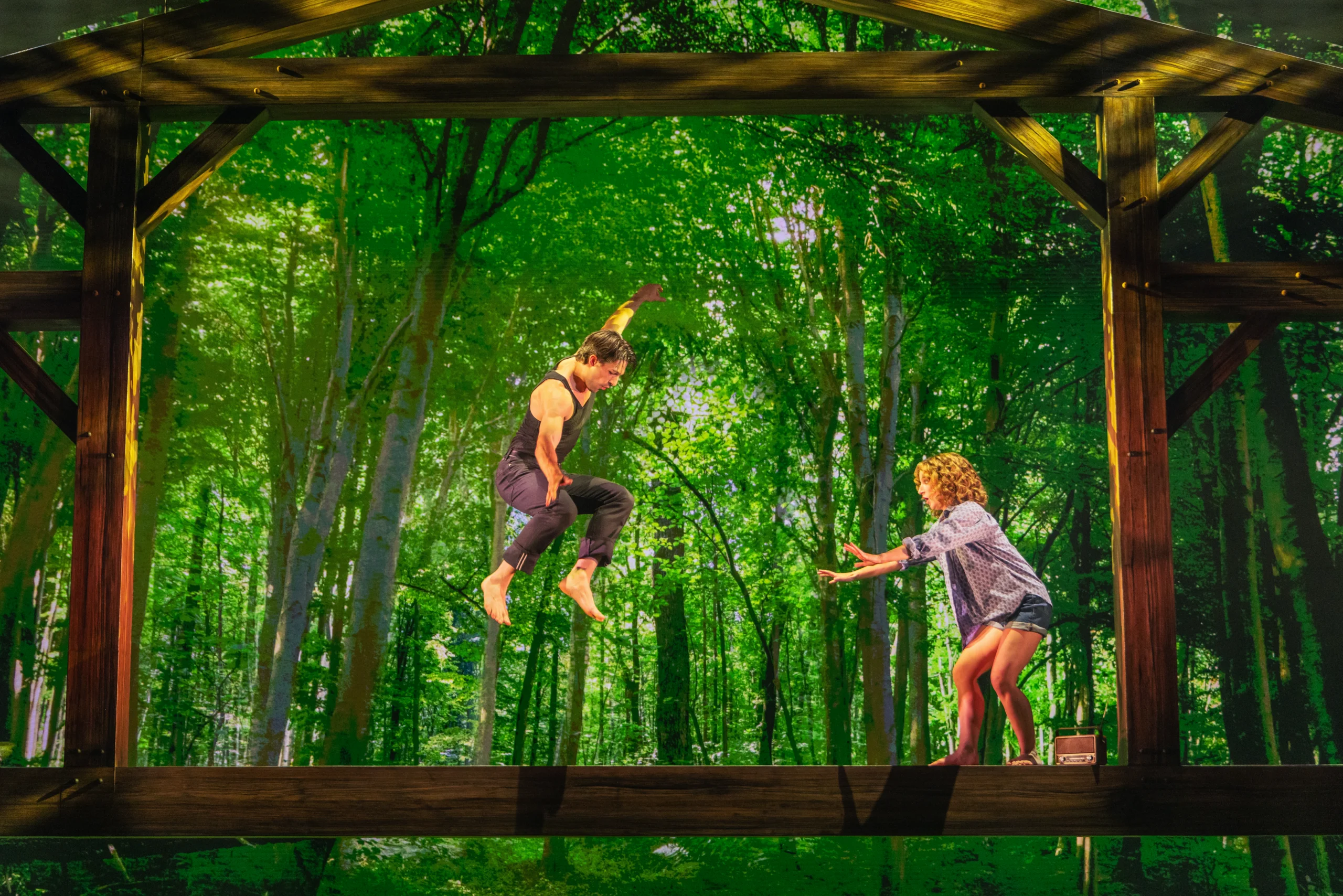 Two performers on a forest-themed stage during a dance scene from Dirty Dancing: The Musical.
