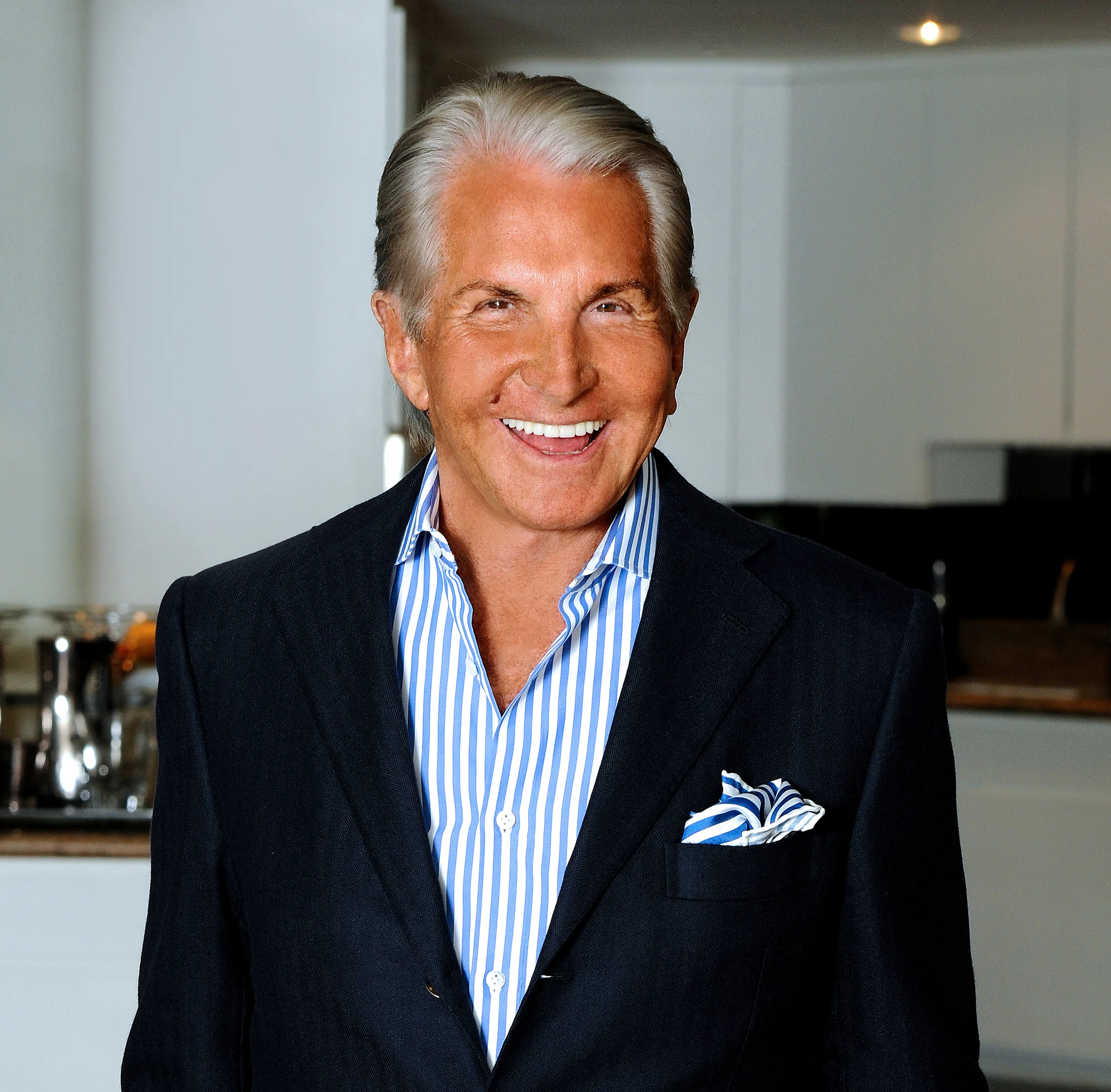 George Hamilton George Hamilton wearing a blazer and a blue and white striped shirt, smiling.