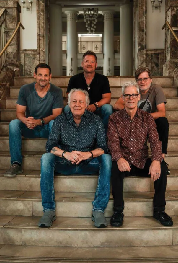 Little River Band promotional group portrait featuring five musicians seated on a grand staircase inside a historic interior setting. Professional concert photography showcasing the legendary rock band's live performance experience at the Kravis Center.