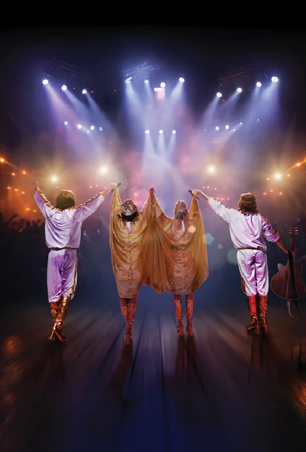Four performers in white and gold costumes take a bow onstage under concert lights during an ABBA tribute show.