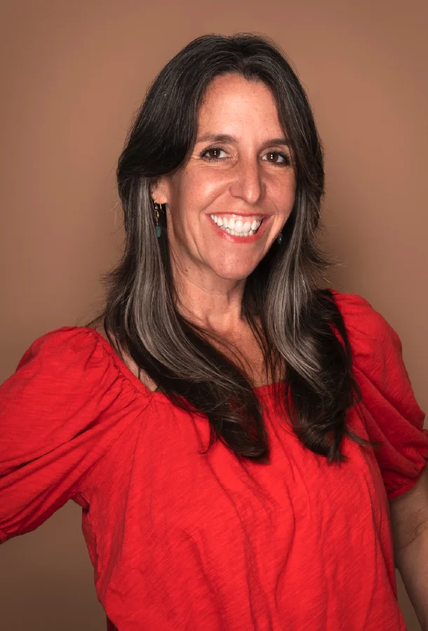 Professional portrait of arts educator and speaker Marisa Palazzolo wearing a red blouse against a neutral background.