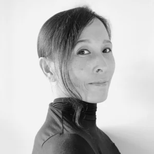 Black-and-white portrait of Shizu Yasuda wearing a dark high-neck top, photographed in profile against a light background.