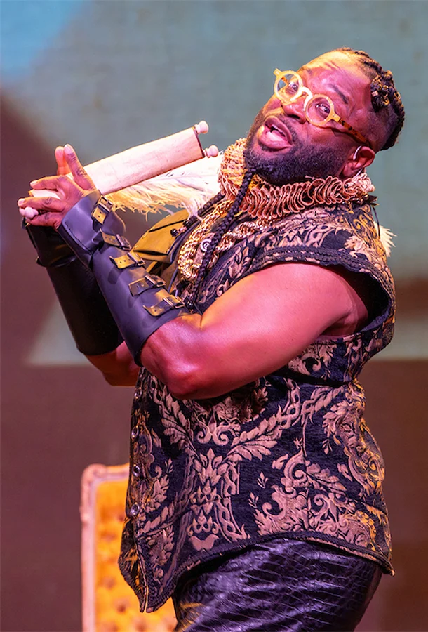 Performer in elaborate Renaissance-style costume holding a theatrical prop during The Bard in Bars.