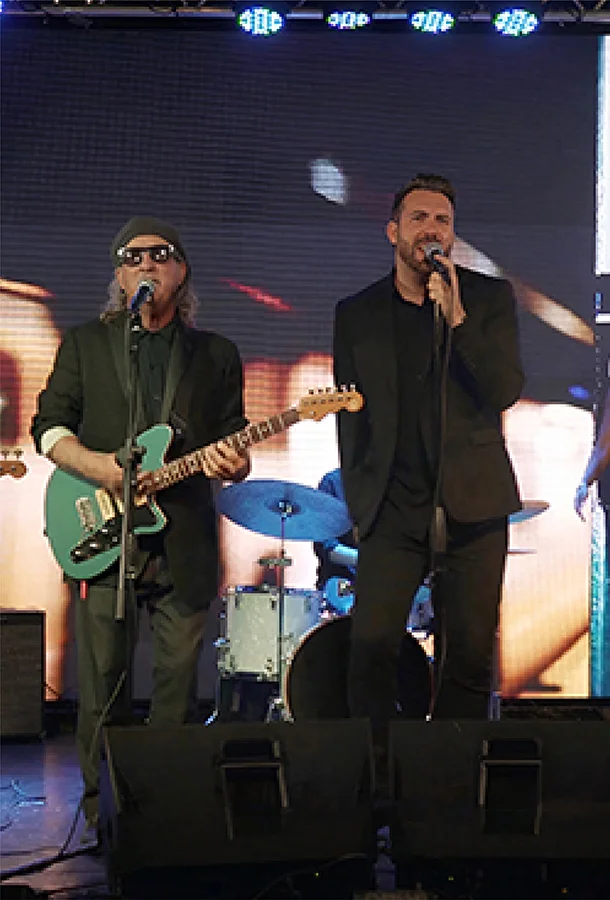Musicians perform on stage with electric guitar, vocals, and drums during a live concert by The Expanding Man.