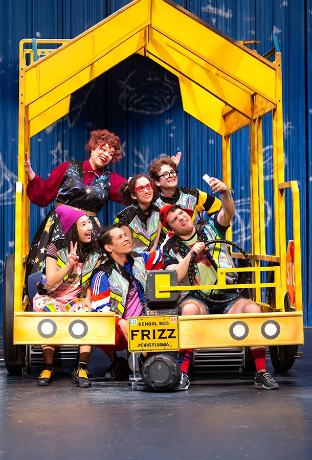 Performers inside a yellow school bus set in The Magic School Bus: Lost in the Solar System stage production.