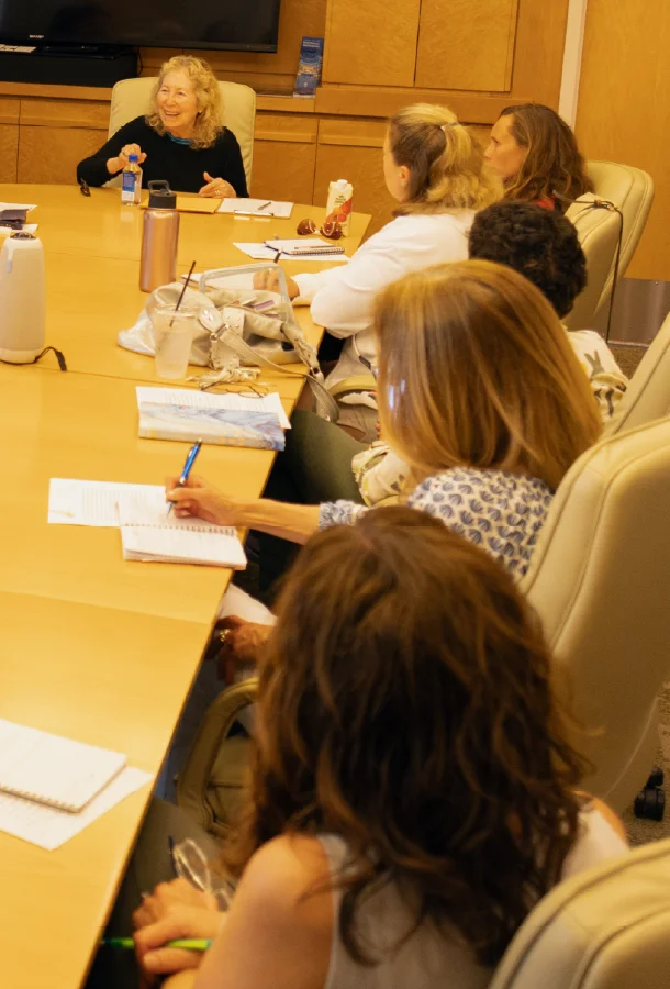 Participants seated around a conference table taking notes and engaging in a creative writing workshop.