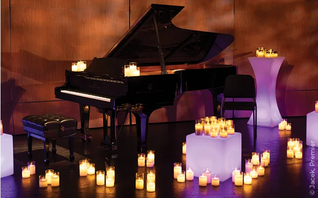 Grand piano surrounded by candles on a concert stage.