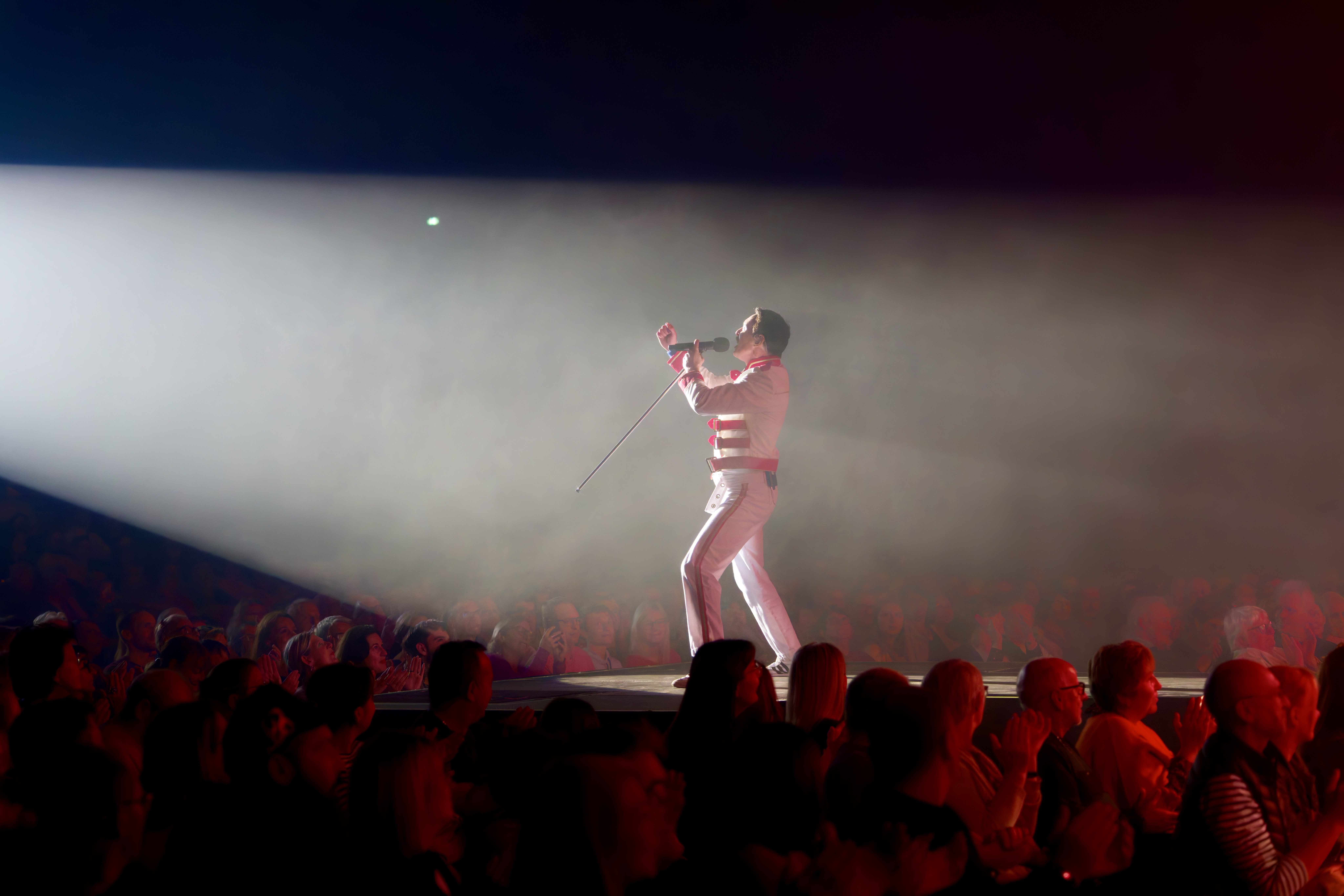Gary Mullen sings in the spotlight on stage.