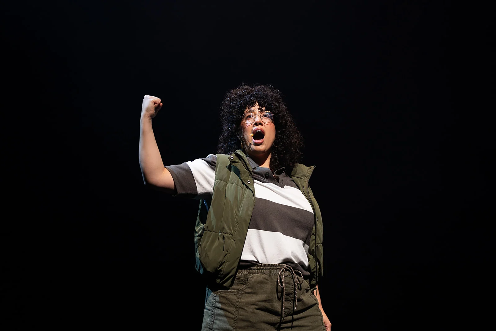 Actress singing with outstretched arm.